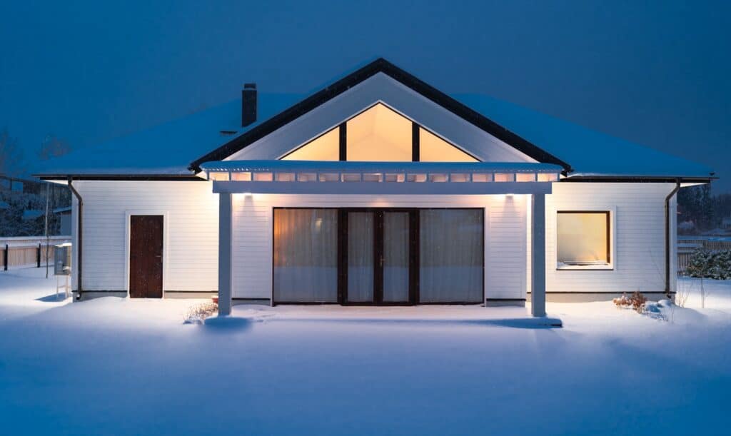 A house is lit up at night in the snow