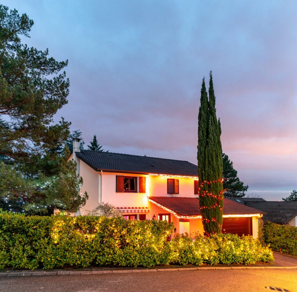 white and brown concrete house near green trees under gray sky during daytime