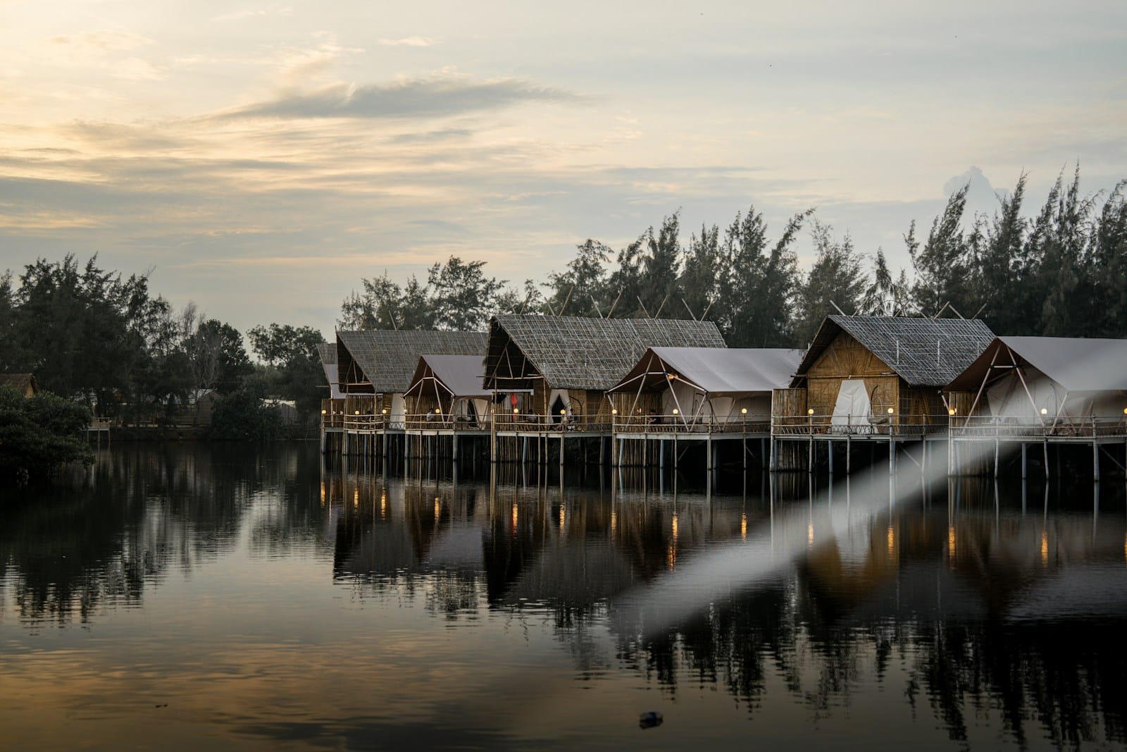 Wooden cabins over a lake reflect the sunset. (Govee Outdoor Permanent Lights) | Make Them Truly Permanent With Our Mounting Clips