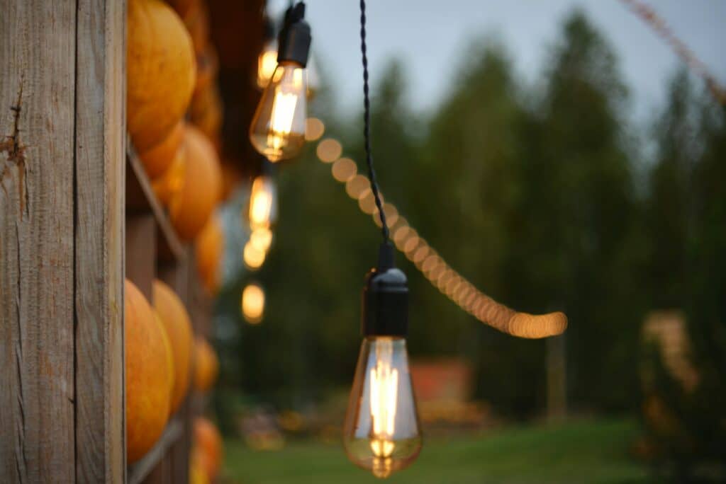 Pumpkins and glowing edison bulbs at dusk.