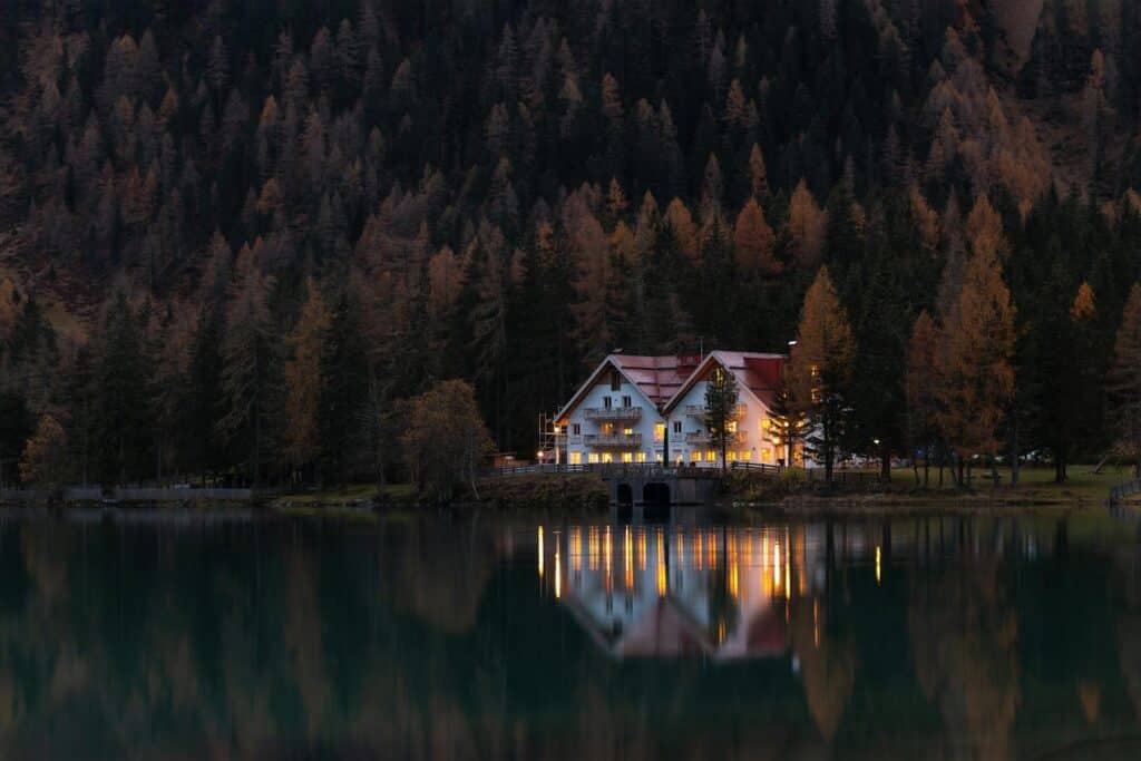 Scenic autumn view of a lakeside house reflecting on calm waters at twilight.