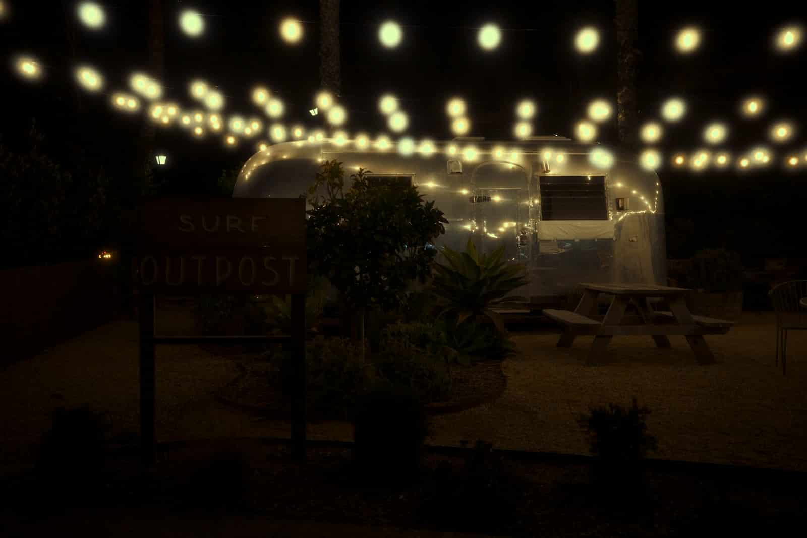 Airstream trailer lit by string lights at night