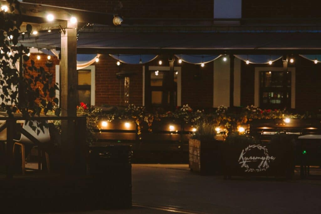 Outdoor restaurant seating area at night with string lights.