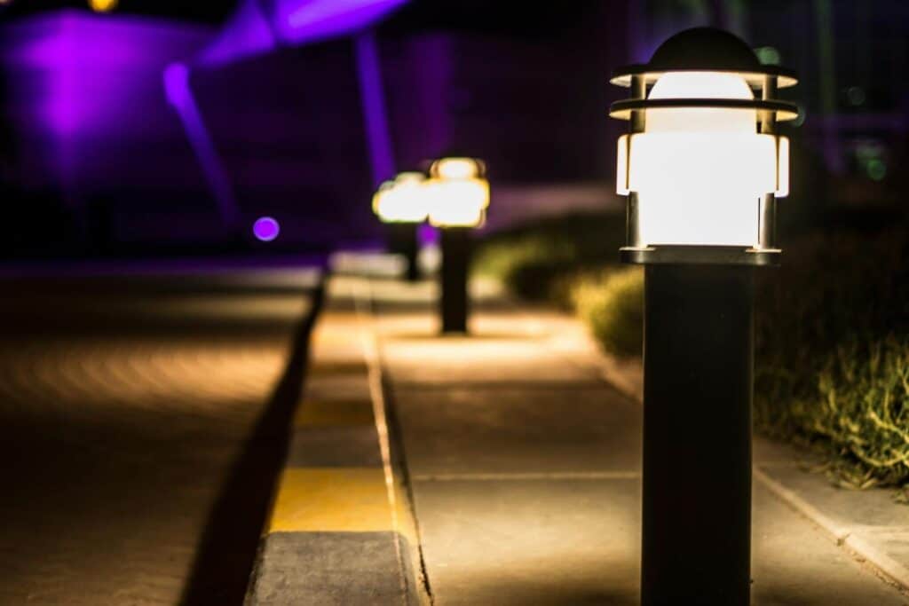 A scenic night view of illuminated lamp posts lining a paved path with a bokeh effect.