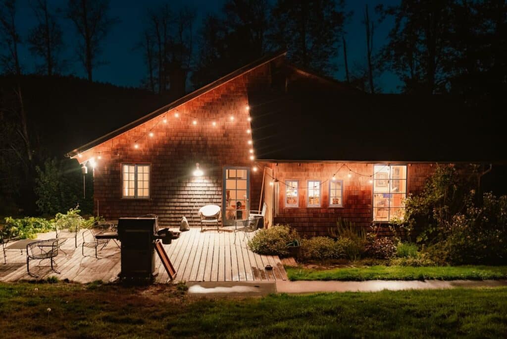 A charming wooden cabin with string lights creates a warm, inviting atmosphere in a nighttime outdoor setting.