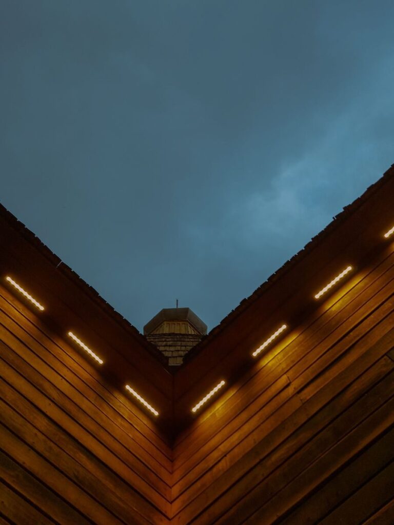 Illuminated architectural corner with lights against a darkening sky, captured at dusk.