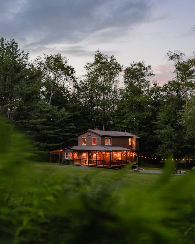 A house is lit up at night in the woods