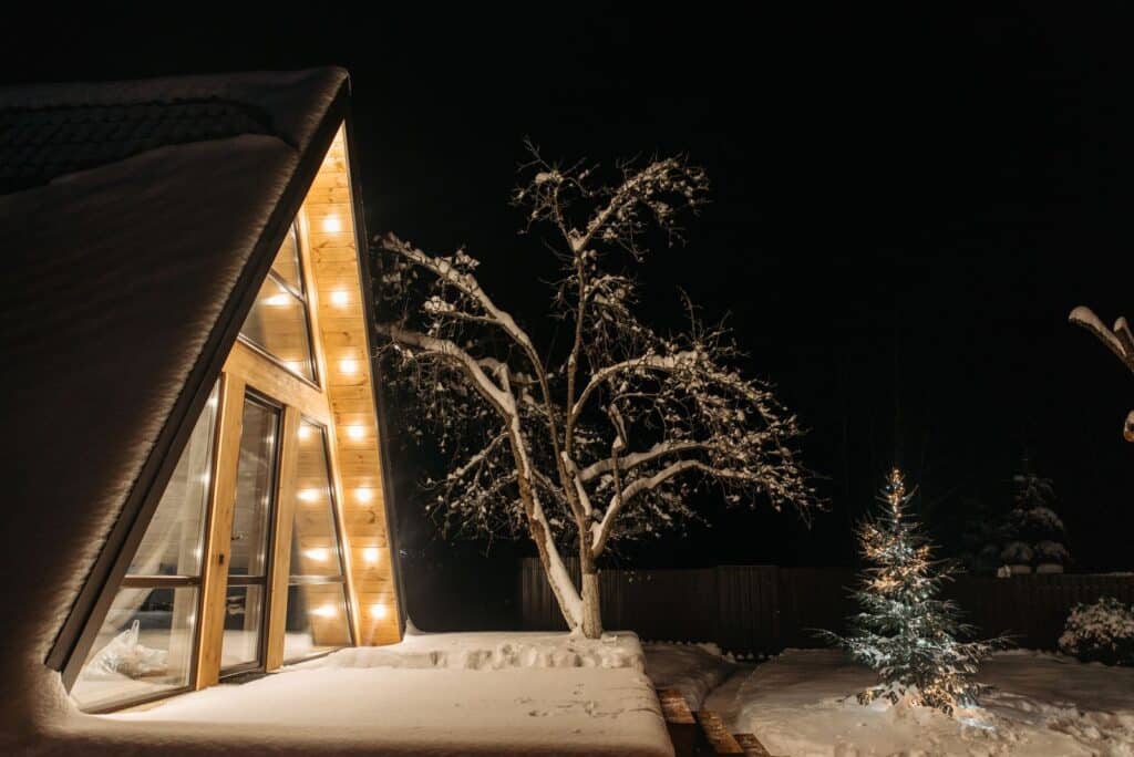 A beautifully lit cabin in a serene snowy landscape under the starry night sky, perfect for winter getaways.